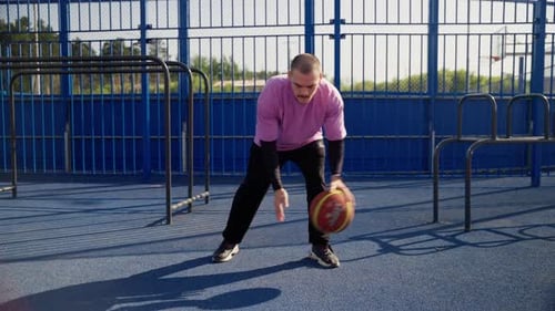 Skillful Young Man Dribbling Basketball on Outdoor Court in Slow Motion