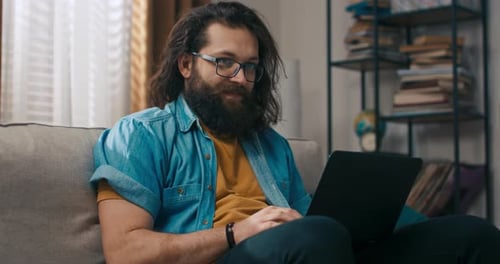 Man Relaxing on Couch Using Laptop Computer