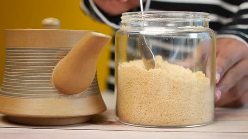Pouring White Sugar in a Tea Cup