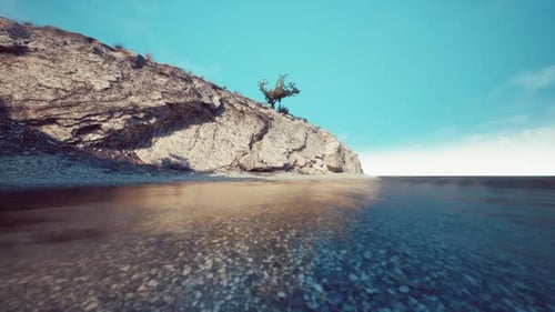 A Tranquil Beach Landscape with Clear Water and Rocky Shoreline During Daytime