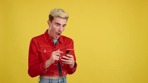 Young Adult Reacting to Smartphone on Yellow Background