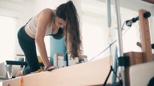 Woman Doing Pilates on Reformer Machine