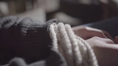 Tied hands with rope in a dark horror place.