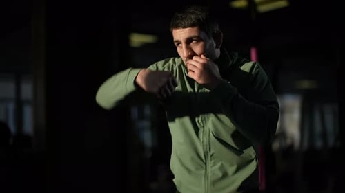 Muscular Boxer Shadow Boxing with Intense Punches Displaying Powerful Athletic Movement in Dimly Lit