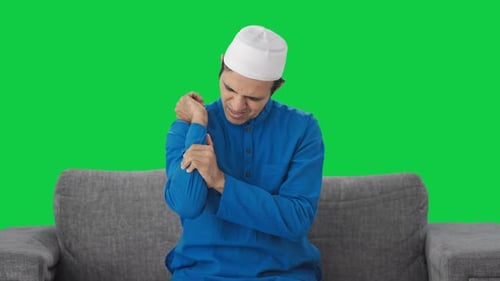Sick Muslim man suffering hand pain Green screen