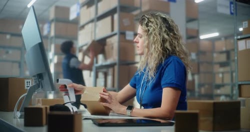 Female Logistics Specialist Scans Parcel Using Barcode Scanner Checks Data Using Computer
