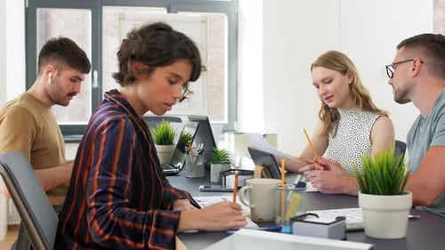 Diverse startup team collaborates on app design in modern office setting