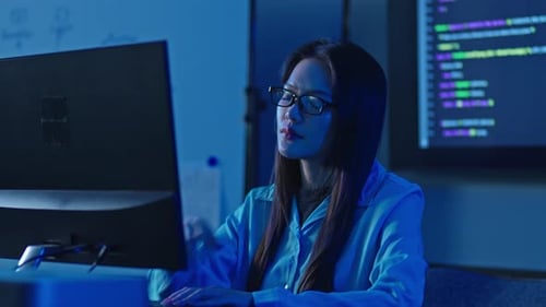 Ernsthafte asiatische Programmiererin debuggt Code auf Computermonitor