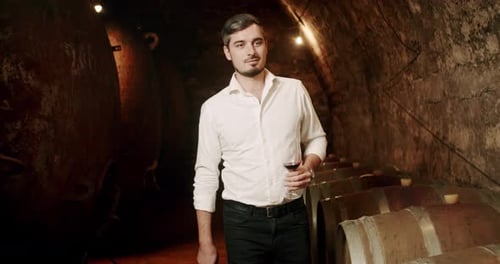 Young Man Holds Wine in Historic Cellar