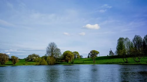 Un sereno lapso de tiempo en un paisaje primaveral con árboles en flor y reflejos en un lago tranquilo bajo un azul brillante
