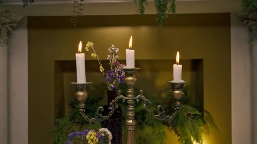Close-up of burning candles standing in a candlestick on a table next to flowers in an restaurant