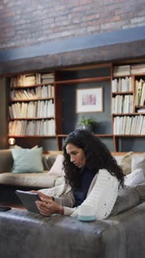 Woman Relaxes on Couch Using Tablet at Home