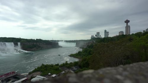 Panoramic view of Niagara Falls, water flowing down the waterfall creating steam, on a moody day