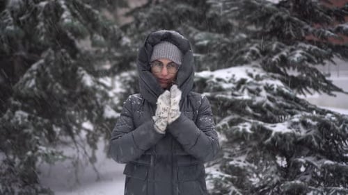 Woman in Winter Warming Hands in Snowfall