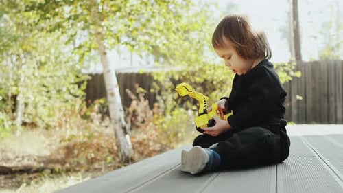 Child Playing with Toy Tractor Outdoors