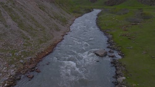 Push in reveal of a river that goes through tall snowy mountiain in a grassland