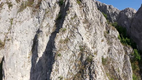 Flying through vertical limestone walls in a deep gorge, canyon, rock climbing aerial