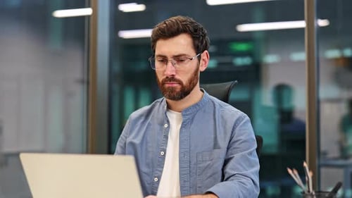 Businessman Working on Laptop in Office Thinking and Planning Project