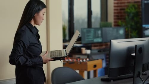 Asiatischer Softwareentwickler nähert sich dem Schreibtisch mit einer Laptop-Programmierschnittstelle