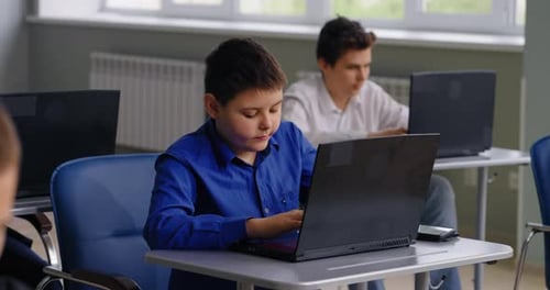 Schüler, die im modernen computergestützten Klassenzimmer mit Laptops arbeiten, Porträt eines jugendlichen Jungen
