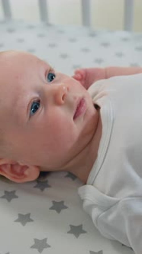 Portrait of a Playful Little Baby is Smiling Cheerfully Through the Sides of the Crib Joyful Lovely