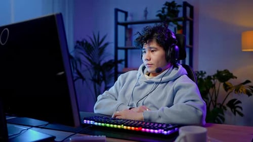 Young Adult Playing Computer Game With Headset