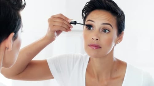 A beautiful young woman applying mascara