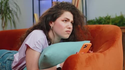 Woman Lies on Couch Looking at Mobile Phone