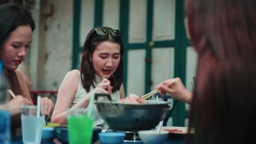 Asian friends sharing and eating hotpot together