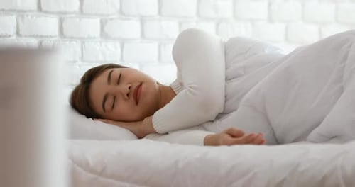 Une femme dort avec un purificateur d'air dans une chambre blanche confortable pour le filtre et le nettoyage