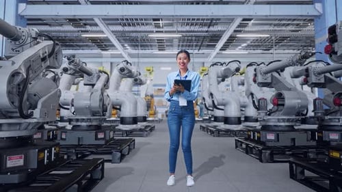 Woman Inspecting Robotic Arms in High Tech Factory