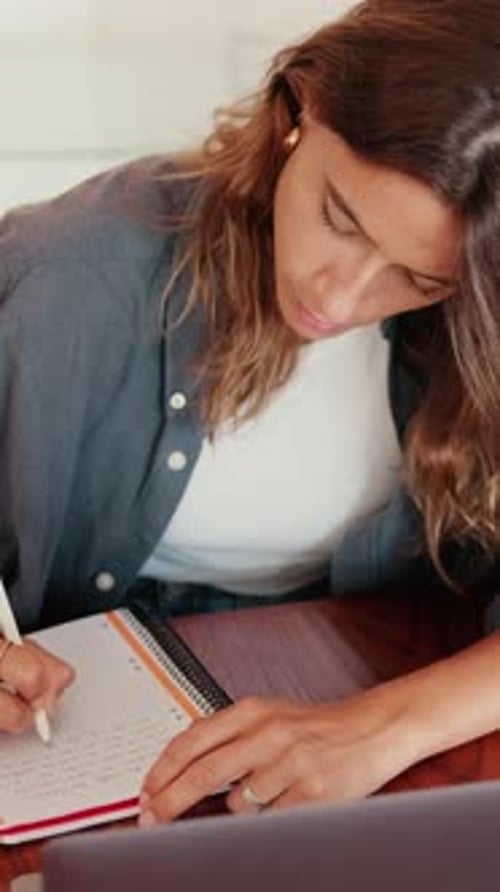 Woman Writing in Notebook with Laptop Close Up