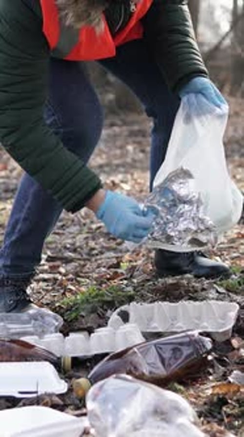 Woman Volunteer Picking Up Trash in Nature Setting