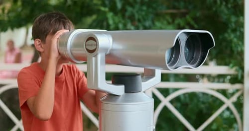 Boy Looks Through Binoculars Outside on Sunny Day