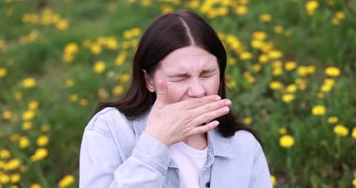 Seasonal allergy. Woman sneezing in park on spring day