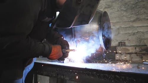 Welder Works on Metal in Urban Workshop