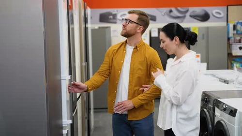 Young Couple is Viewing Fridge in Home Appliances Store
