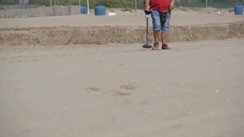 Man with a Metal Detector Walks Along a Sandy Beach on the Seashore Slow Motion