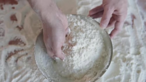 The cook in the bakery kneads the dough with his hands and begins to prepare bread.
