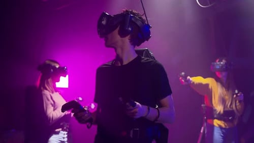 Group of people playing VR games in a studio with blue pink neon lights