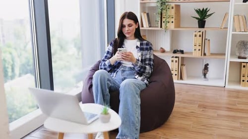 Woman Relaxing in Beanbag Chair Using Smartphone