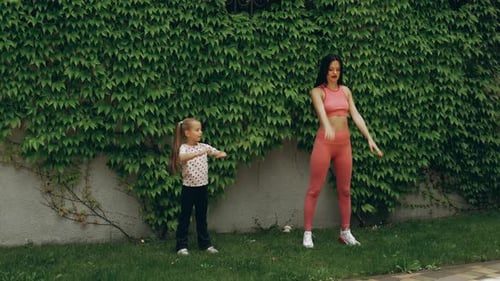Mother and Daughter Workout in a Garden on a Sunny Afternoon