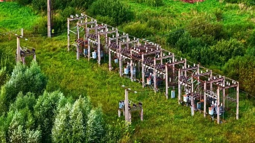 Outdoor electric substation surrounded by grass and trees in rural area from above