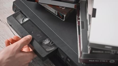 Male Hand Inserts VHS Cassette Into a VCR Video Recorder