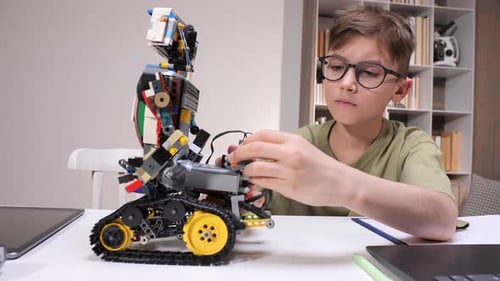 Junge mit Brille konzentriert sich auf den Bau und die Programmierung eines Blockroboters und lernt etwas über