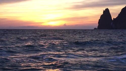 A Red Burning Sunset Over the Sea with Rocky Volcanic Cliff