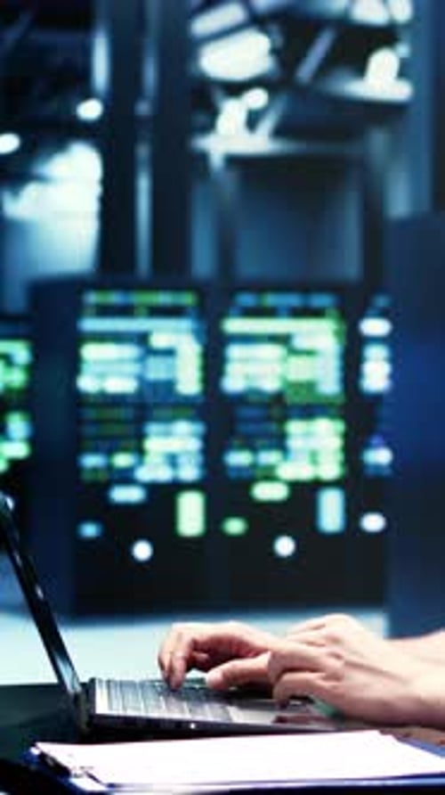 Close-Up of Hands Typing on a Laptop in a Modern Server Room