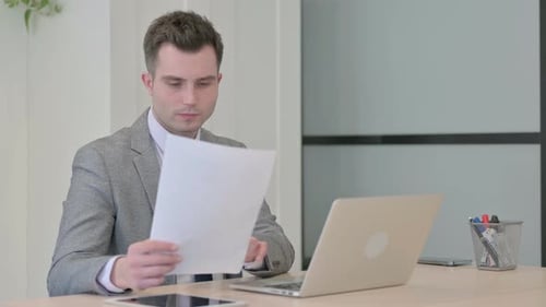 Young Businessman Working on Laptop and Documents
