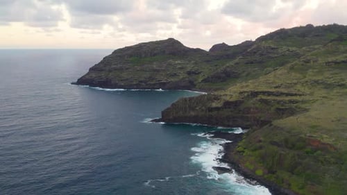Aerial view 4k footage by drone of ocean blue waves break on high cliff of a rocky mountain. Danger