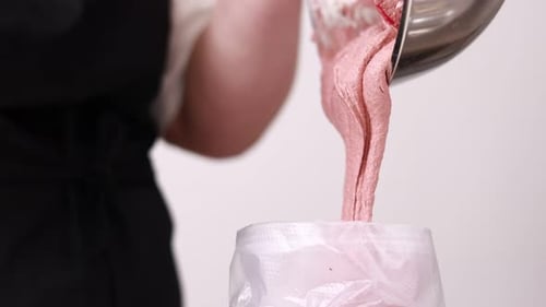 A woman confectioner putting in pastry bag with colourful macaroon dough for further use. Process